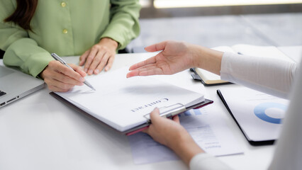 Asian businesswomen signing important contract document during formal meeting modern office setting making strategic agreement