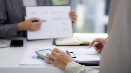 Asian business professionals collaborate on financial analysis reviewing data charts during an office consultation session for strategic planning