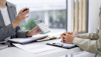 Adult business professionals analyze financial data using calculator documents collaborate discuss strategy successful business growth modern office environment