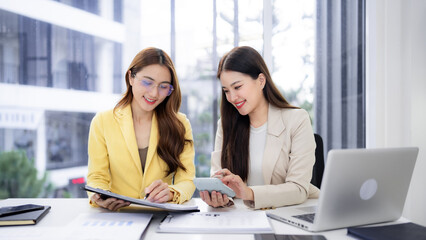 Asian adult businesswomen collaborate analyze financial data modern office setting productive teamwork success achieving goals happy professionals discuss project strategy