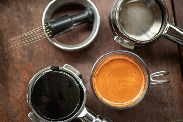 Portafilters and Espresso Shot Arranged on Wooden Table, Focus on Coffee Making Tools and Crema...