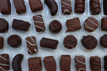 Close-up of inside of a white chocolate box with many assorted chocolate pralines