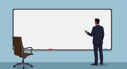 A businessman in a suit stands pointing at a blank whiteboard in an office setting with a chair nearby.