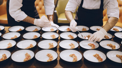 Chefs in a professional kitchen plating gourmet appetizers with precision, demonstrating teamwork and the final stages of a fine dining experience.