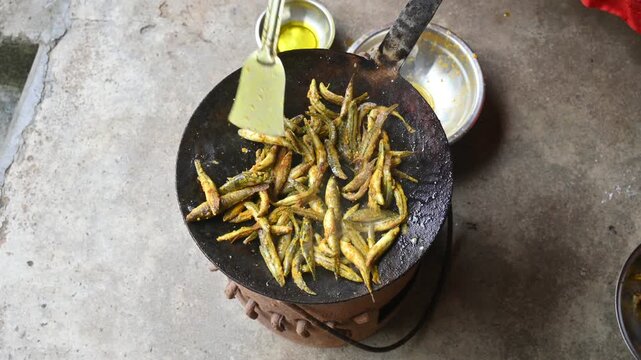 Small Snakehead or Channa orientalis Fish being fried in a pan. Fish are typically marinated with spices like turmeric, salt, and chili powder before being deep fried until they are crispy and golden.