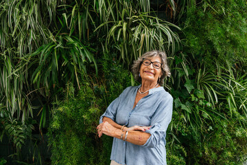 Smiling senior woman posing by living green wall