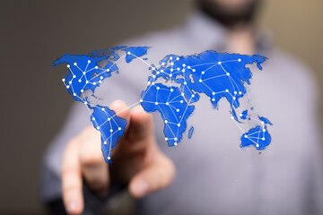 A hand points to a digital world map overlaid with a network, representing global business, internet connectivity, and worldwide communication i