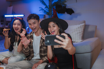 Friends taking selfie celebrating halloween party at home