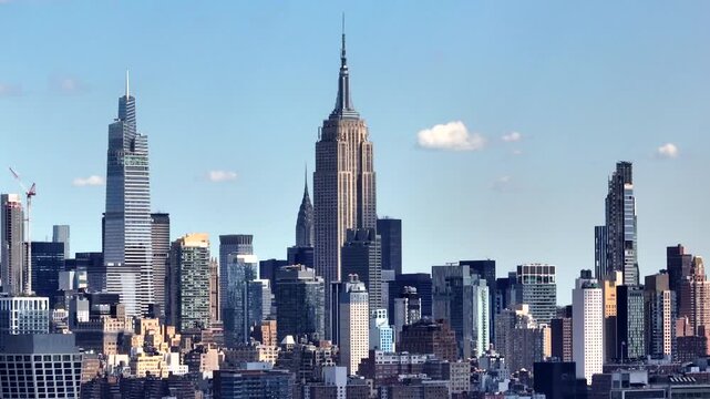 New York City skyline view from Hudson River showing glass office towers and unique architecture reflecting blue sky and clouds on a summer day
