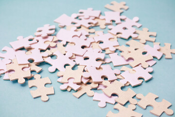 Fototapeta premium Pile of unfinished light pink jigsaw puzzle pieces scattered on a blue surface representing challenge