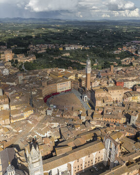 Aerial view of the Piazza del Campo's shell shape and the Torre del Mangia standing tall amid the warm hues of the city, Siena, Tuscany, Italy.