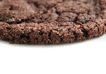 Chocolate cookie close up. Brown cookie corner or edge with sea salt. Just baked cookie. Snack or dessert. Selective focus. White background.
