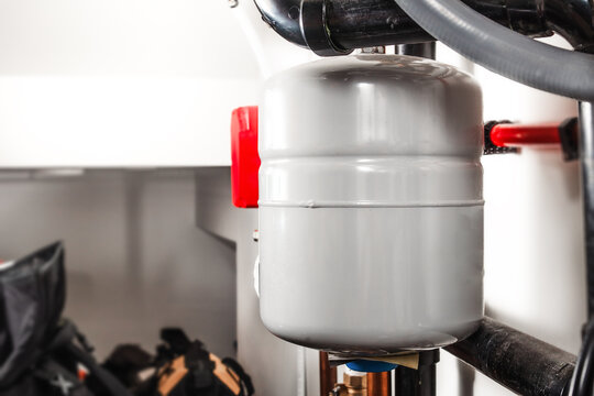 Pressurized expansion tank for hot water heating in storage room. Water expansion tank for closed loop hydronic heating system. Thermal expansion tank or expansion vessel. Selective focus.