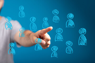 Close up of a human hand pointing at a blue digital screen with numerous person icons, representing...