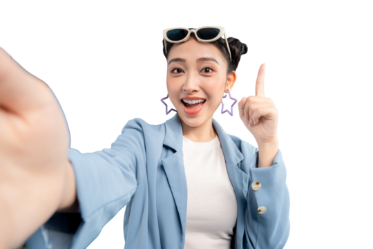 Portrait young Asian woman joyfully taking selfie photo while wearing sunglasses, in her hands. She points her index finger up with exciting gesture on PNG