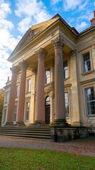 Fototapeta premium Grand neoclassical building with imposing columns against a blue, partly cloudy sky