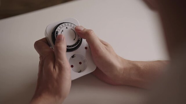 Male hands setting timer switch, controlling electrical devices with precision for optimizing energy management in residential and industrial environments. Concept of modern smart technology.