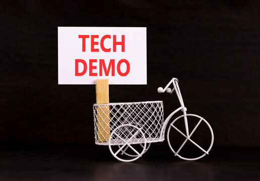 Tech demo symbol. Concept word Tech demo on beautiful white paper. Beautiful wooden clothespin. Miniature white bicycle. Beautiful black background. Business tech demo concept. Copy space.