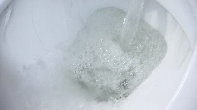 White toilet bowl flushing water in bathroom