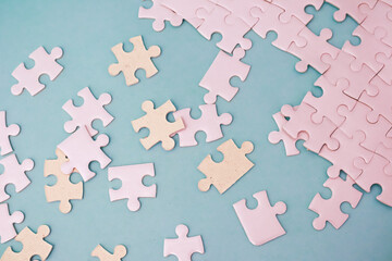 Pastel jigsaw puzzle pieces scattered on a light blue surface evoke a sense of playfulness