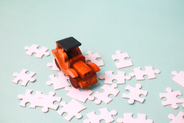 Obraz premium Creative Toy Arrangement Featuring a Wooden Car and Puzzle Pieces on Blue Background