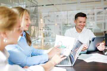 Team collaborates in modern office during meeting with devices and documents