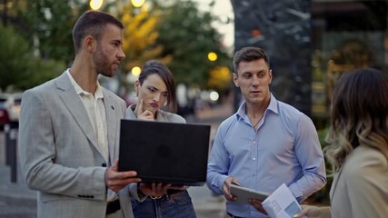 A dynamic group of young business professionals conducts an outdoor meeting, actively engaging in collaborative discussion and strategic planning while reviewing data on a laptop and documents. - Powered by Adobe