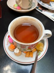 Floral teacup and assorted colorful cookies and snacks, creating a festive, cozy tea presentation : Jogjakarta, Indonesia - October 03, 2025