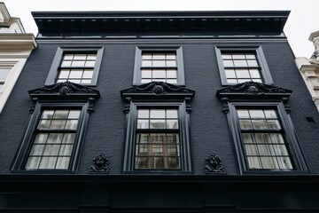 Obraz premium Beautifully designed black building facade featuring intricate details on the upper sections of the windows in a historic urban setting during the day