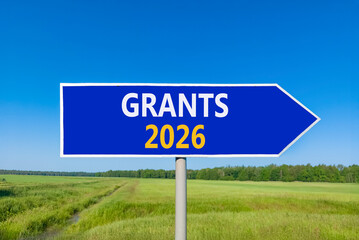 Grants 2026 symbol. Concept words Grants 2026 on beautiful blue road sign. Beautiful green grass field forest and blue sky background. Business and grants 2026 concept. Copy space.