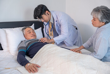 Obraz premium scene of elderly man patient lying on bed getting examine from a doctor,and his wife encourage beside