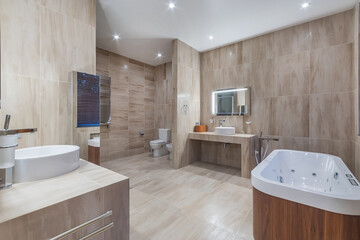 The spacious modern bathroom is decorated in beige tones, with elegant fixtures and a serene atmosphere for relaxation and recuperation.