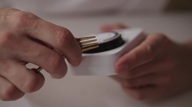 Man manipulating timer switch with metal fork, revealing dangerous electrical interaction against isolated white surface, close-up. Concept of energy management and smart home control, slow motion.