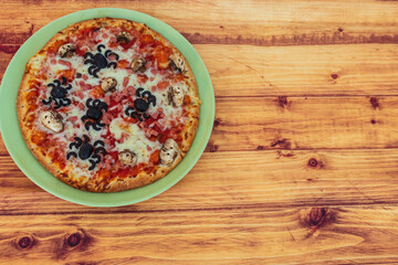 Halloween pizza with spiders and skulls on wooden table. Top view