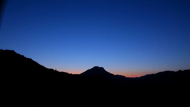 A majestic mountain silhouette against a twilight sky, radiating calm and natural beauty.