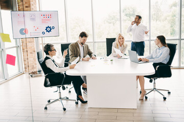 Professional teamwork and discussion in a bright modern office, diverse coworkers collaborating on...