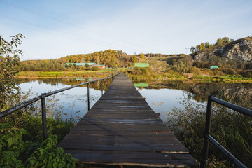 A charming wooden pier extends over a peaceful river in the countryside, especially stunning in autumn, ideal for relaxation and reflection, offering moments to unwind and enjoy natures tranquility