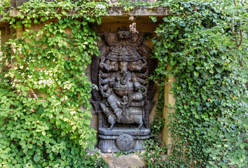 Stone bas relief of Indian multi armed deity with elephant heads on territory of Prague Zoo in Czech Republic