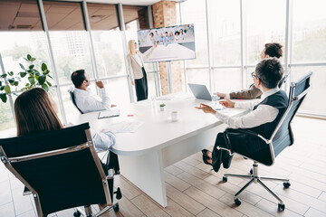 Business professionals collaborate during a meeting in a modern office setting with large windows showcasing an urban view.