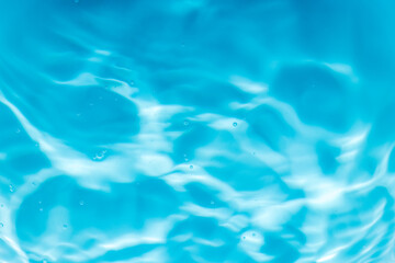 Blue water surface wave macro close up,Transparent blue clear water surface texture with ripples, splashes and bubbles. Abstract summer banner background Water waves in sunlight with copy space.