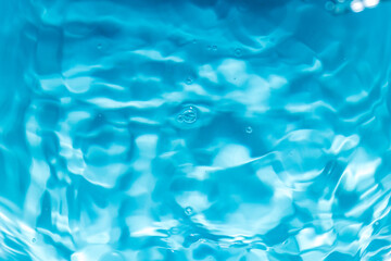 Blue water surface wave macro close up,Transparent blue clear water surface texture with ripples, splashes and bubbles. Abstract summer banner background Water waves in sunlight with copy space.