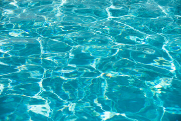 Blue pool water background. Blurred transparent clear calm water surface texture. Water waves in sunlight with copy space.