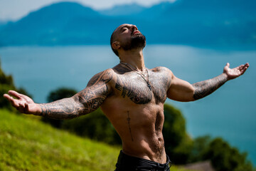 Carefree man in nature. Freedom in nature landscape. Muscular guy breathing fresh air on beauty nature. Handsome topless model with raised hands on mountain nature landscape. Yoga by waterfall.