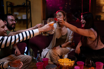 Group of friends toasting drinks together during a cozy indoor gathering