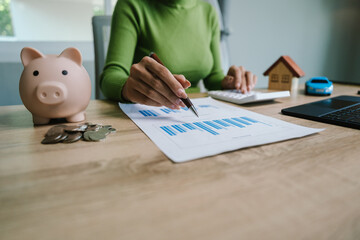 A person saving money with a piggy bank and holding a house model, symbolizing financial planning,...