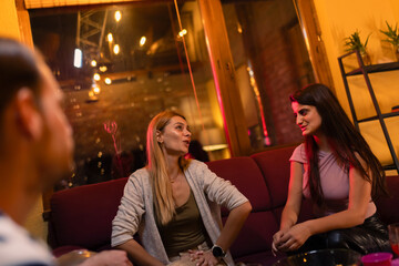 Group of friends enjoying casual conversation in a cozy living room with warm lighting in the evening