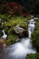 Obraz premium Ethereal long exposure of a stream in Gorbea Natural Park, Bizkaia, Spain, cascading over mossy rocks amidst lush, green woodland
