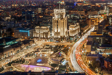 Fototapeta premium Traffic flows along busy streets as the city skyline lights up at night. Modern buildings and historical architecture create a stunning view filled with energy and life.