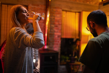 Casual Gathering in Dimly Lit Room With People Socializing and Drinking