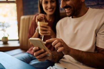 Close up of couple using mobile phone in cafe.